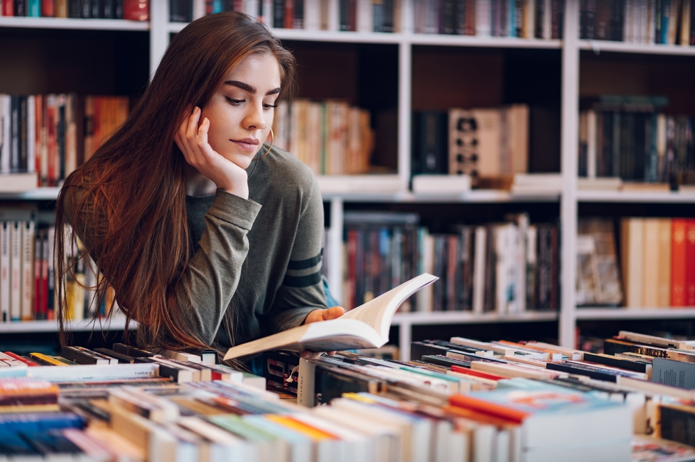 Young Female Customer Reading A Book In Bookstore While Buying - INNOCEAN UK FEBRUARY 2024 REPORT